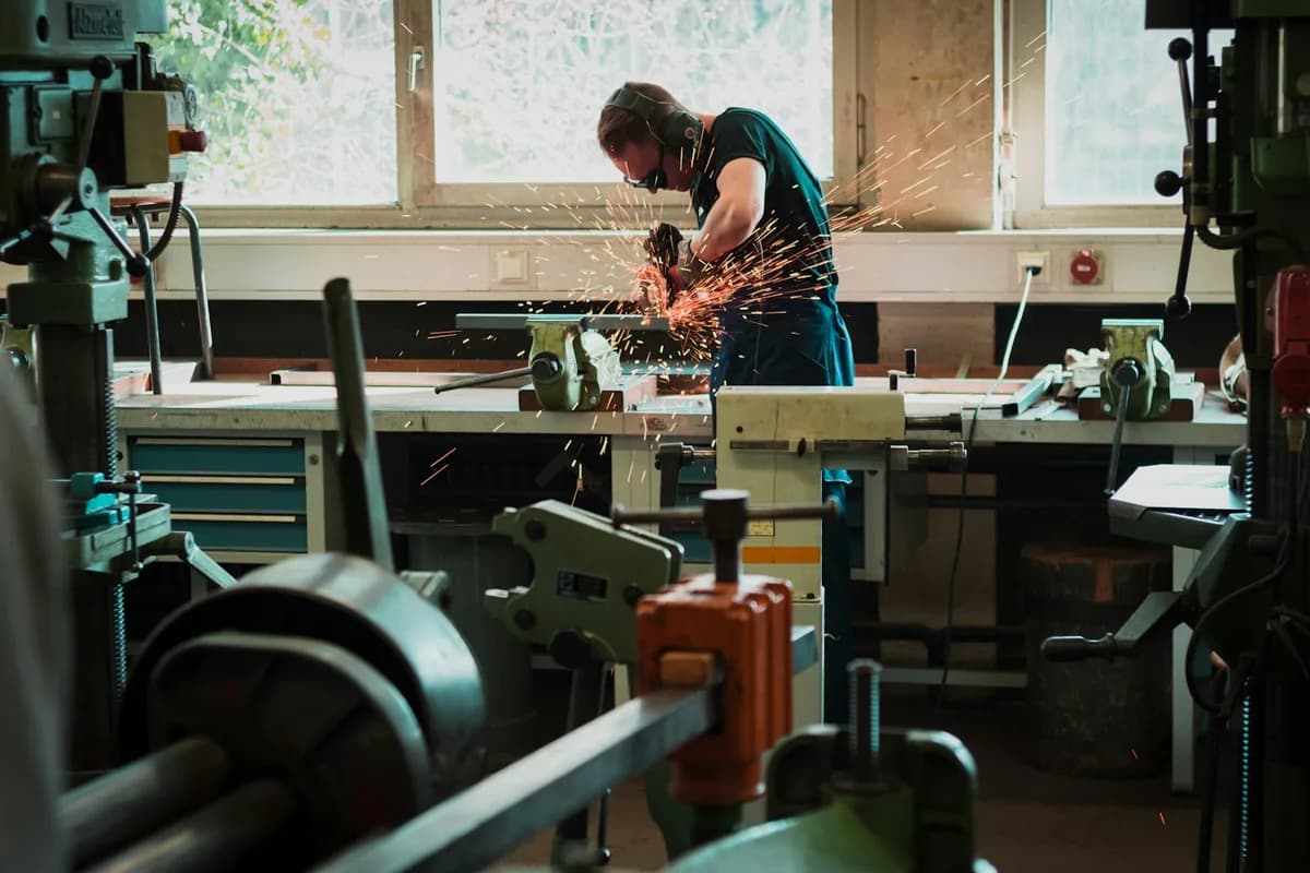 Ein Tüftler trennt Metall an der Werkbank, Funken fliegen