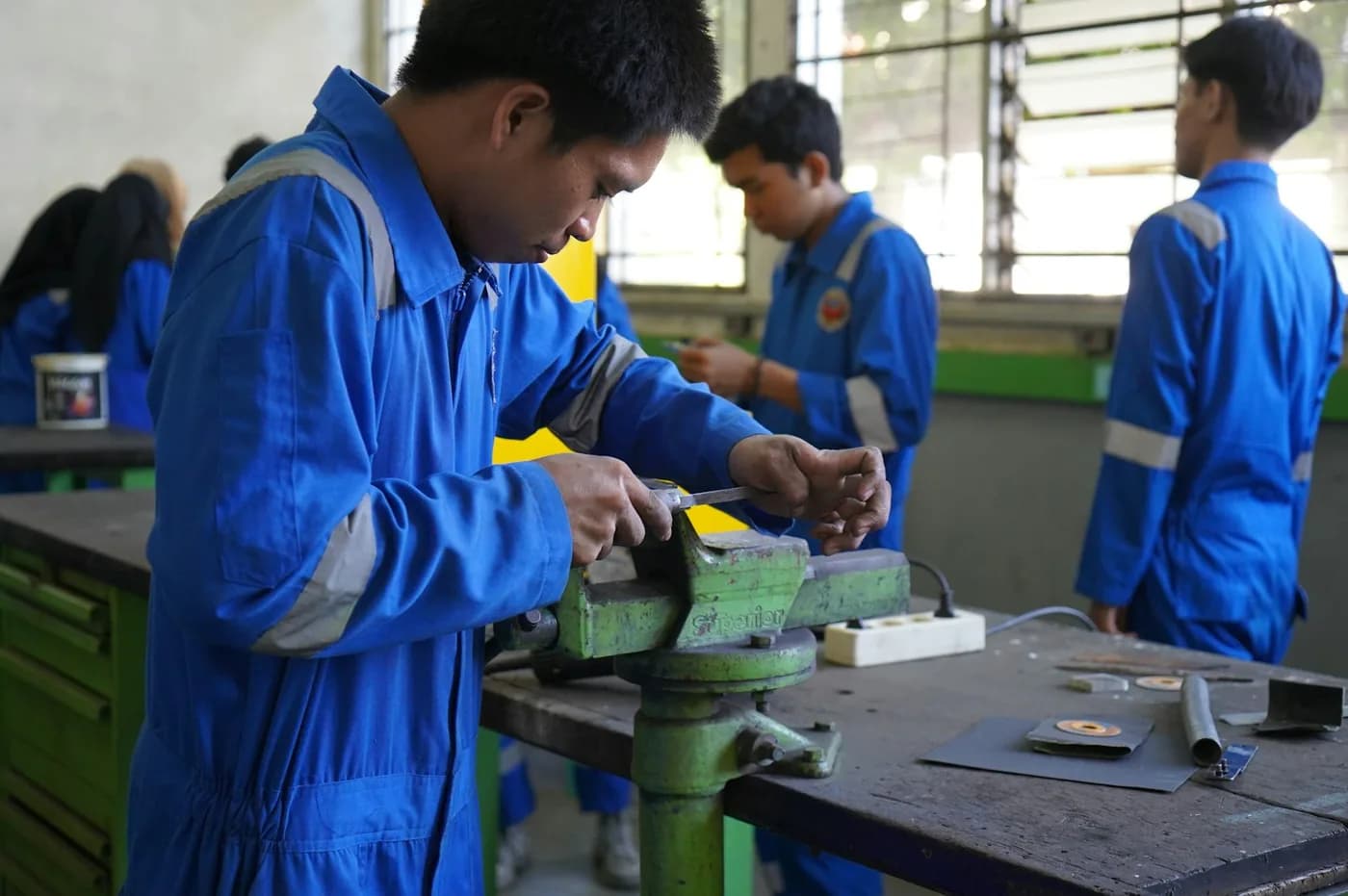 Ingenieurstudierende bearbeiten Metallteile an einer Werkbank